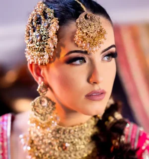 Close-up of a South Asian bride with detailed golden jewelry and elaborate hairstyle, showcasing cultural beauty.
