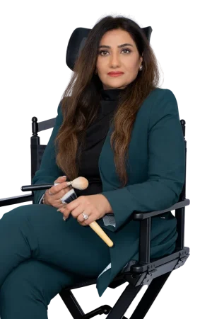 Portrait of Fouzia Rana holding makeup brushes in hand while sitting on studio chair.