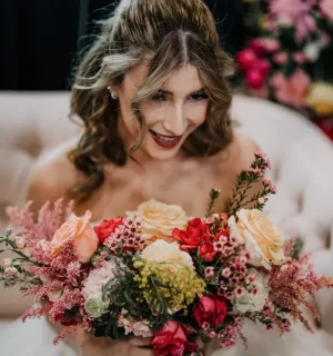 Blonde bride hair Balayage and ethnic makeup glow holding flowers in her hand.